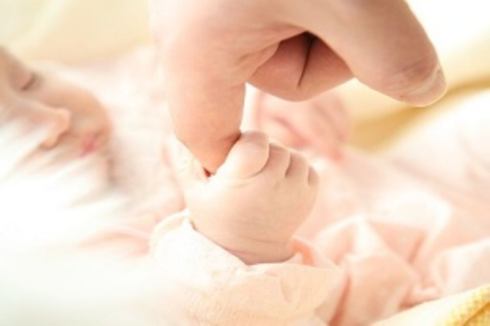 Baby holding onto parents finger
